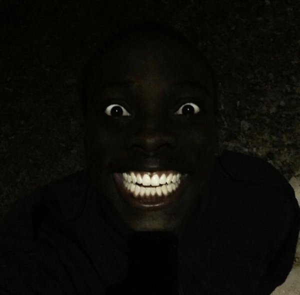 Негр улыбается в темно е