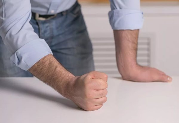 Стучит кулаком по столу