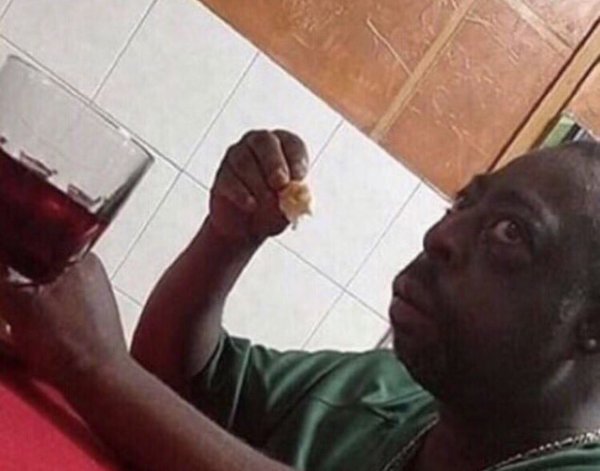 Негр сидит за столом и ест