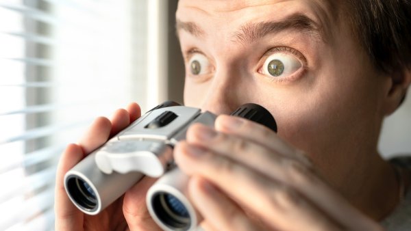 Человек с биноклем в окне