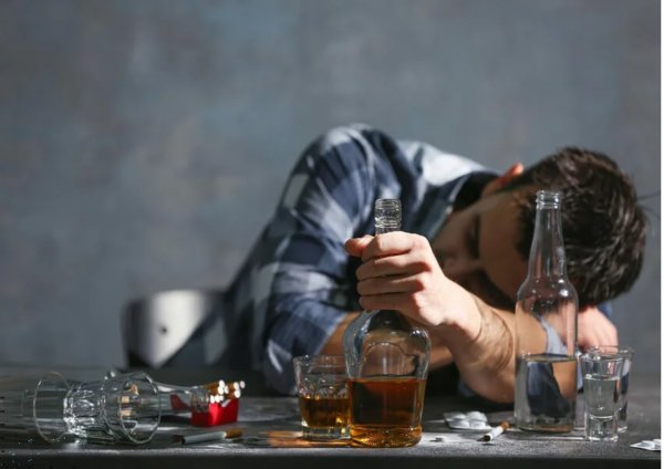 Парень за столом выпивает