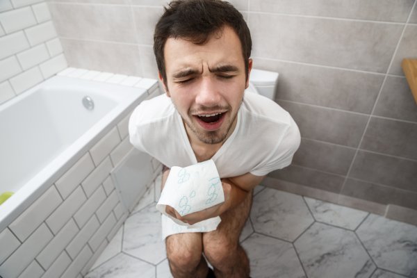 Мужчина стдит на унитаз е