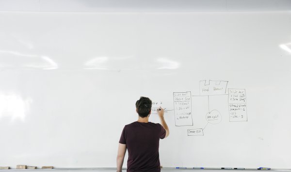 Человек пишет на белой доске