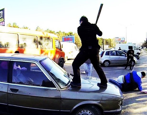 Мужик бьет в стекло машины