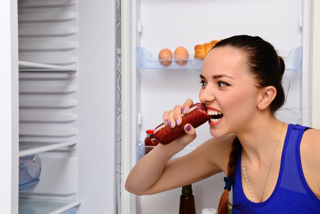 Девушка ест сардельку