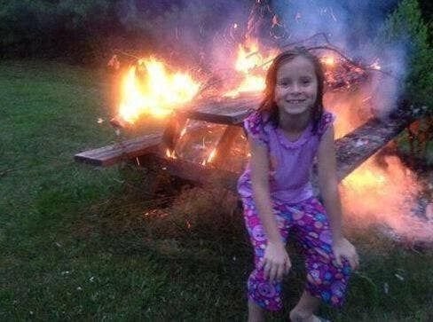 Девочка улыбается на фоне горящего