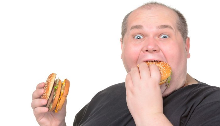 Жирный человек ест бургер