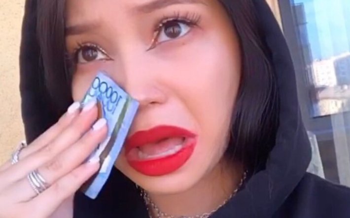 Девушка вытирает слезы купюрами