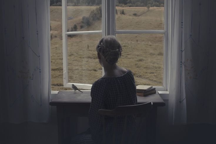 Девочка сидит у окна