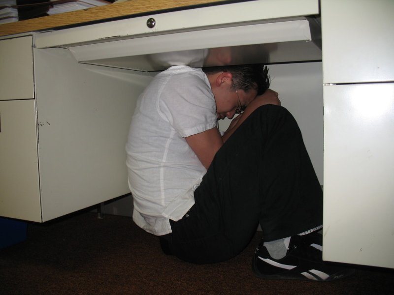 Человек прячется под столом