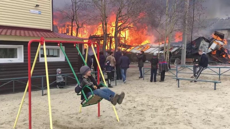 Горящий дом и мальчик на качелях