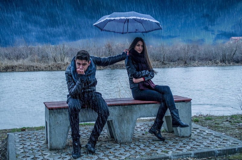 Мужчина держит зонтик над женщиной