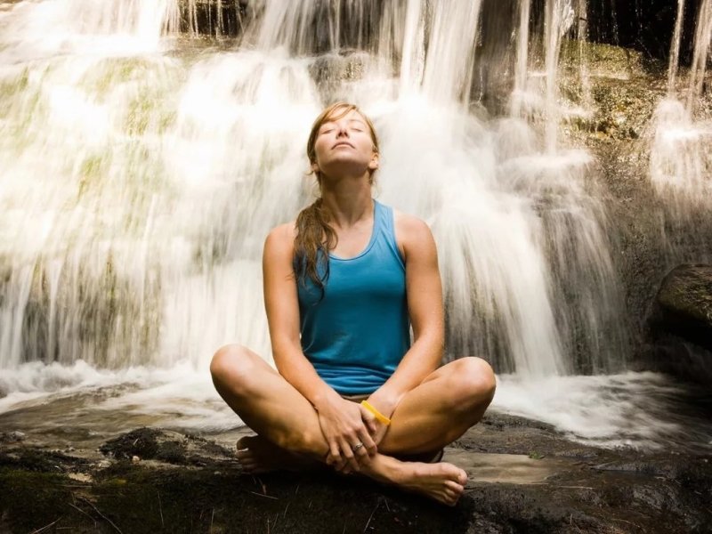 Женщина купается в водопаде