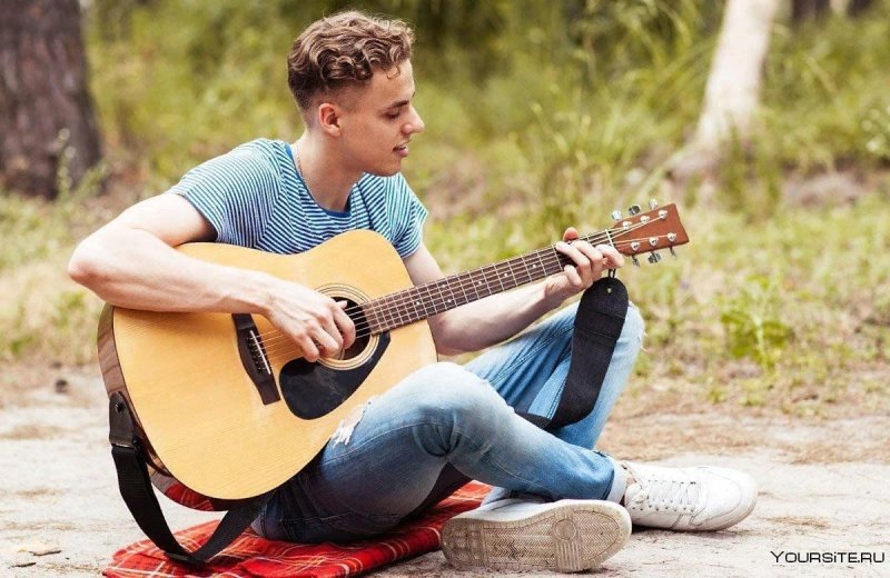 Человек сидит с гитарой