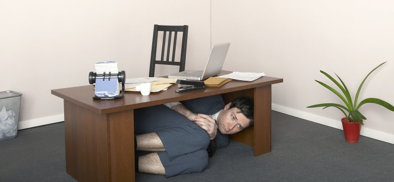 Человек прячется под столом