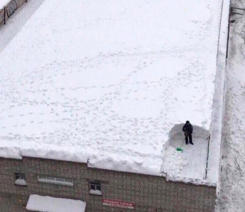 Мужик чистит снег на крыше
