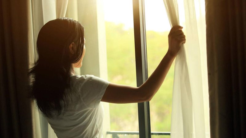 Женщина открывает окно
