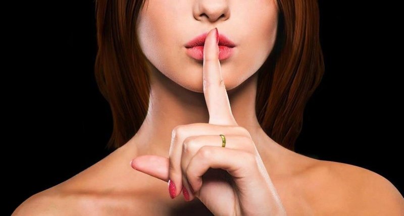 Девушка держит палец у рта