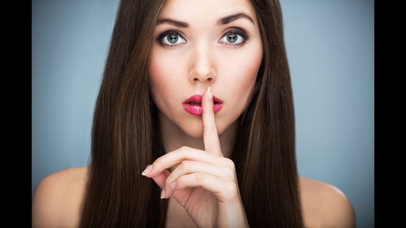 Женщина прикладывает палец к губам