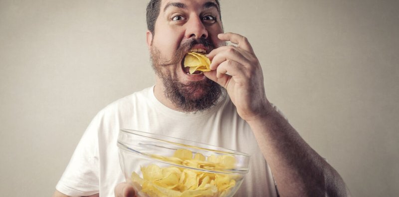 Мужчина ест чипсы