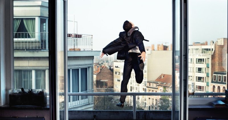 Человек сидит в окне многоэтажки