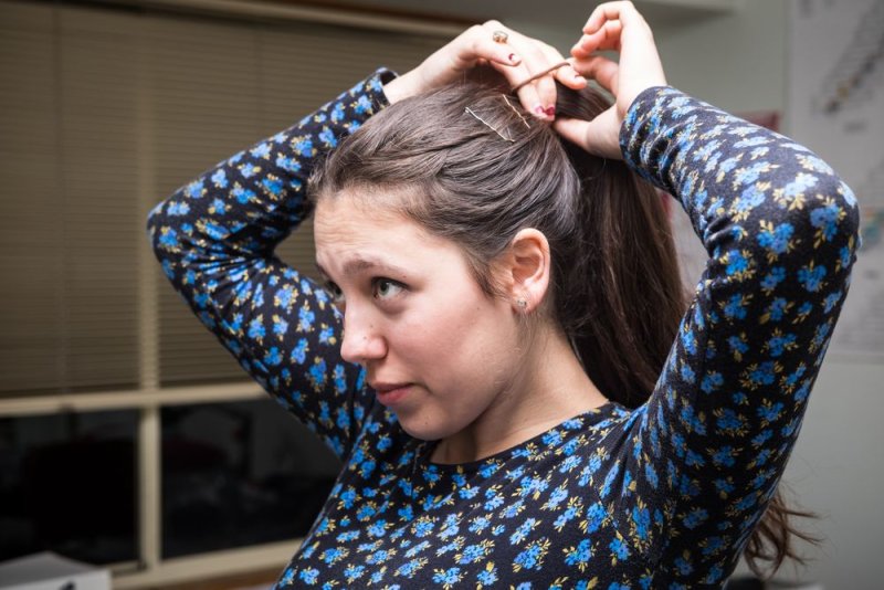 Девушка собирает волосы в хвост