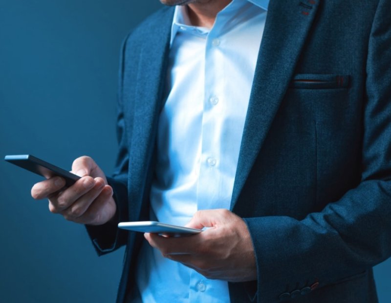 Человек с двумя телефонами в руках