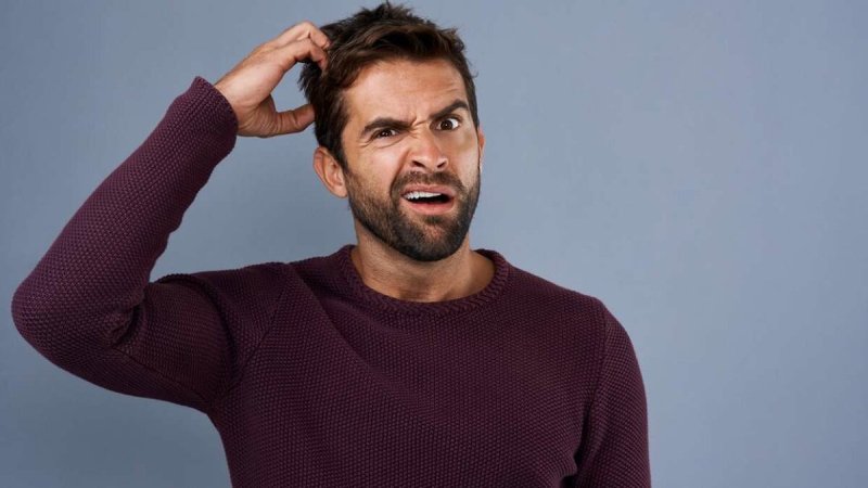 Мужчина чешет голову