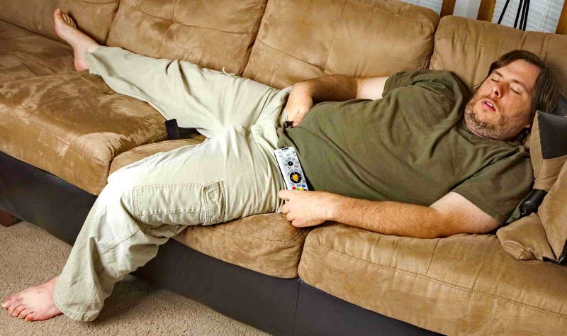 Толстый человек лежит на диване